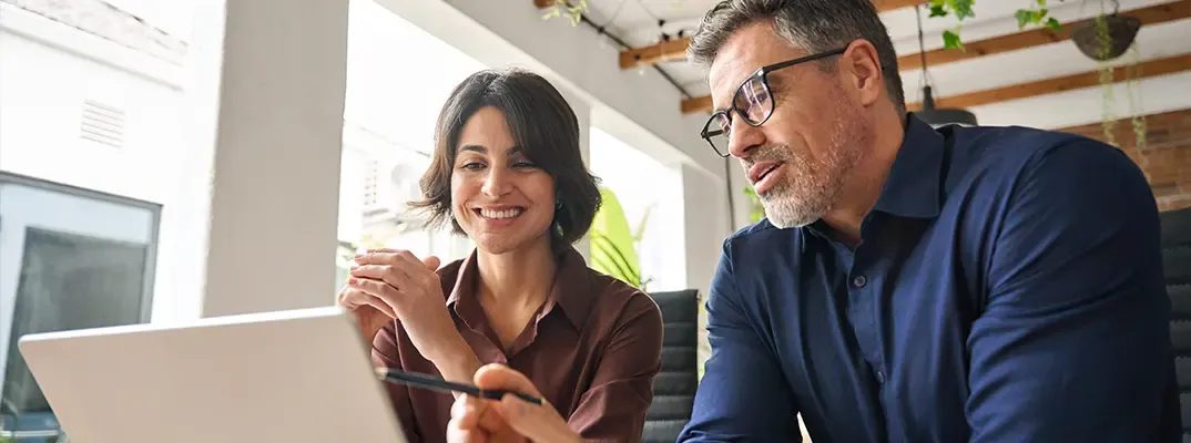A woman and a man working together on a laptop