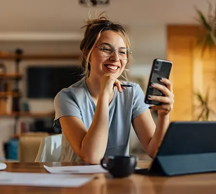A smiling woman paying for her meal at a restaurant using her phone