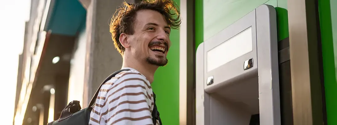 Smiling man in front of an ATM