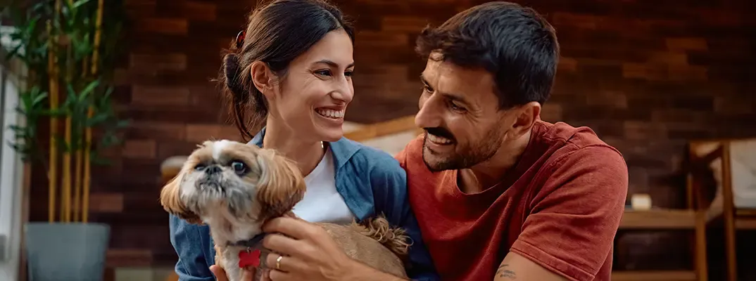 A woman and a man petting a small dog