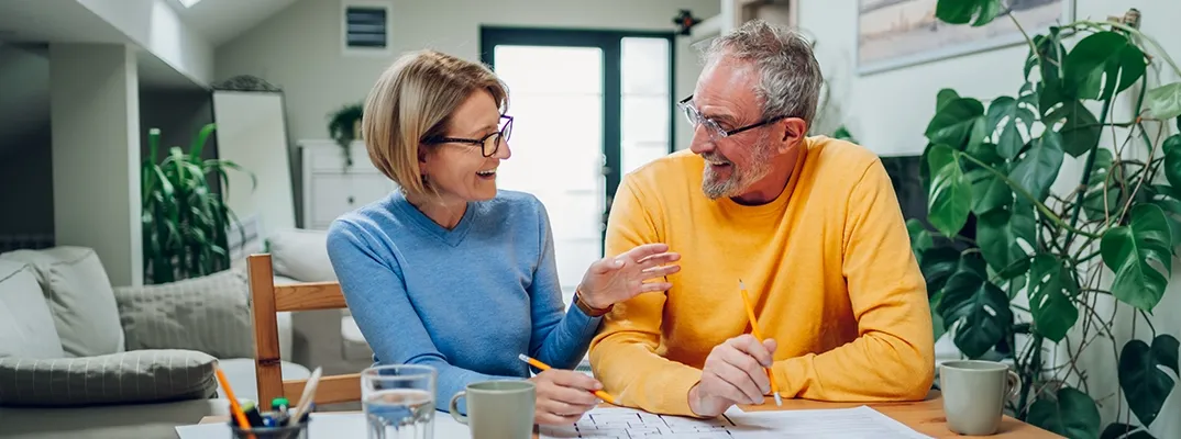 An older couple smiling at each other as they go over a floor plan