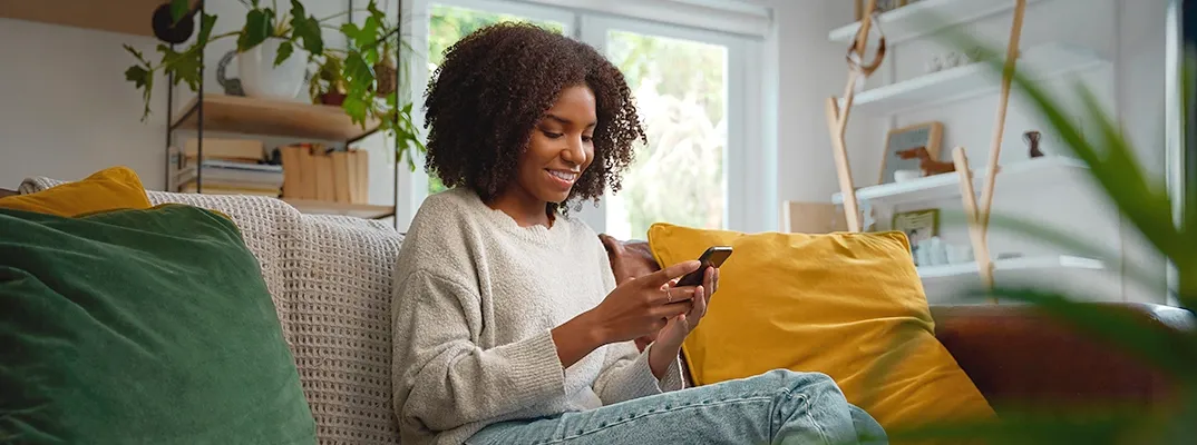 Girl sitting on a couch and looking at her cell phone