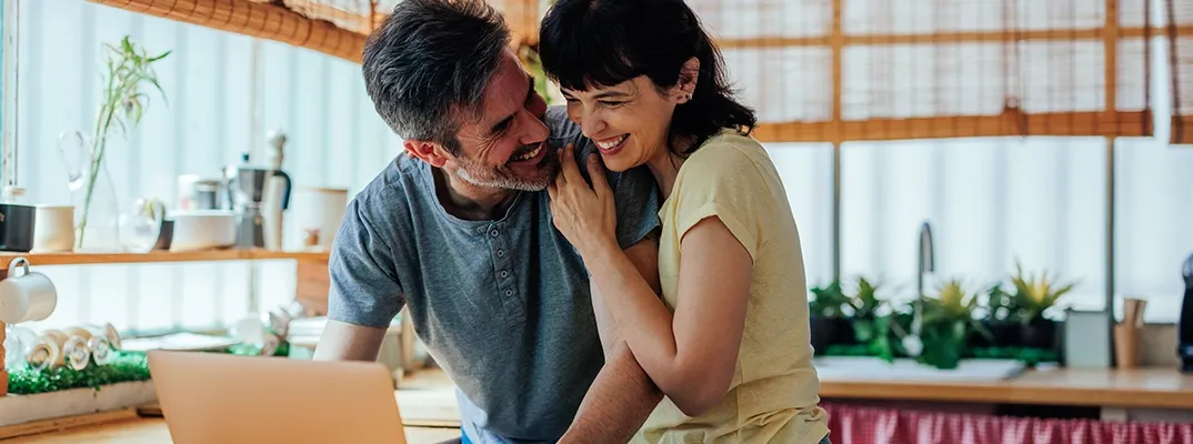 A couple hugging while looking at a laptop