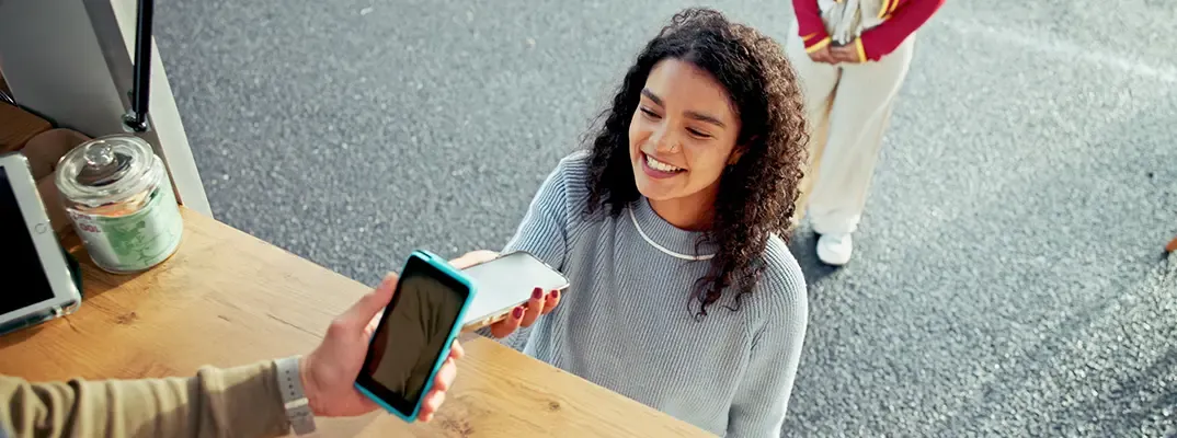 A young woman using her mobile wallet to pay at a food truck.