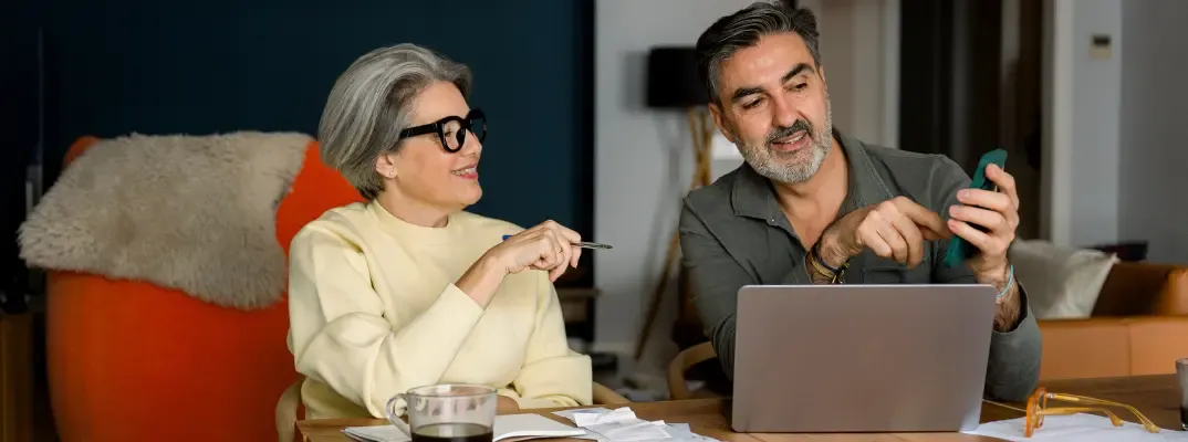 An older couple working on a phone and a laptop