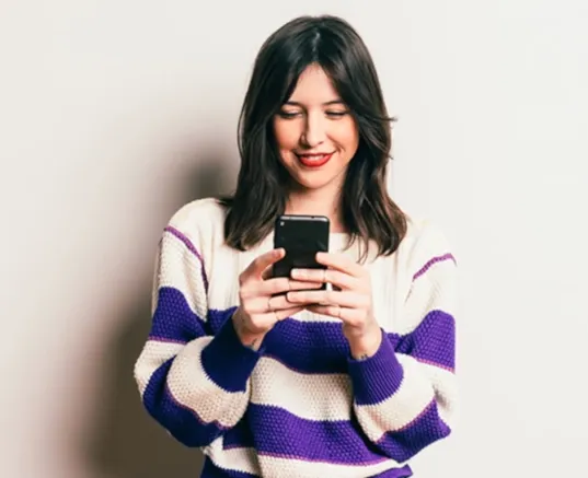 A woman smiling while looking at her phone
