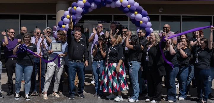 Ivan Olvera cuts the ribbon in front of the South Valley branch during its grand opening while others around him applaud and cheer