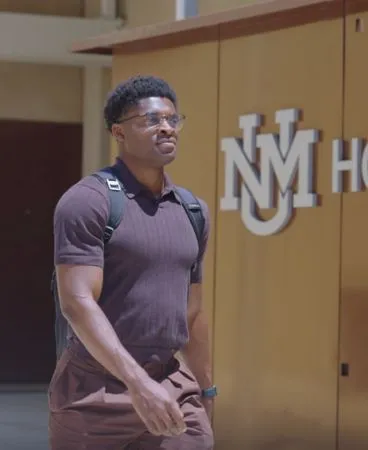 Solomon Gbara, Sunward scholarship recipient, walking on the UNM campus near the Honors College building.