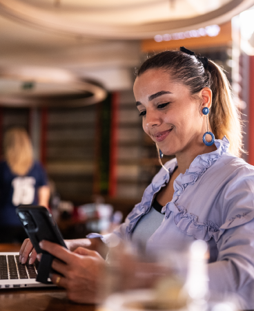 A woman sitting in a lounge area working on her laptop and phone