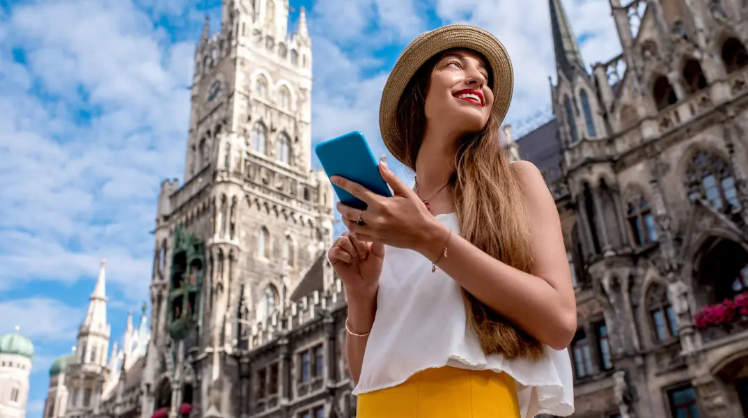 A woman with her smartphone standing in front of a cathedral on a sunny day