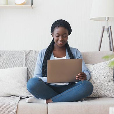 Young woman sitting on couch looking at her laptop computer.