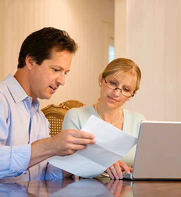 Concerned couple looking at letter they received in the mail.