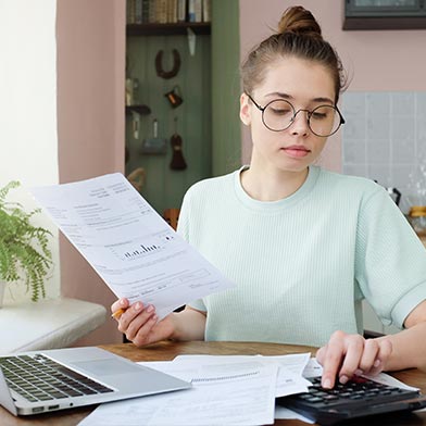 Young woman with glasses using calculator to track her finances