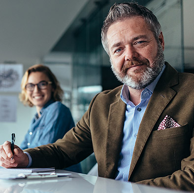 business man and woman seated at table looking at camera