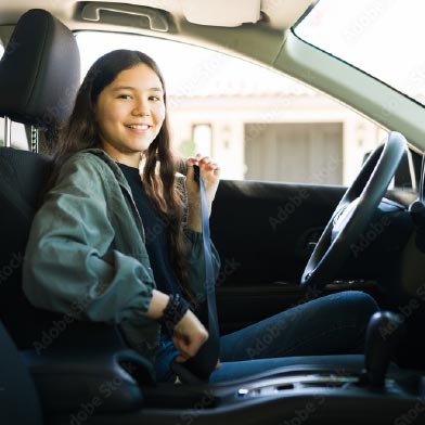 Teen girl smiling while putting on her seatbelt