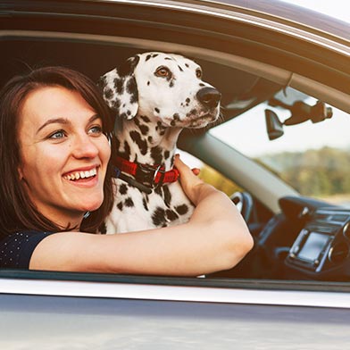 Young woman in car with dog looking out the car window