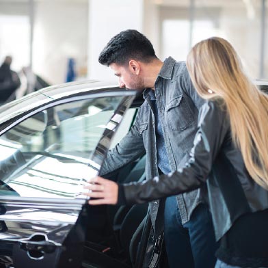 Man and woman inspecting a car at a dealership