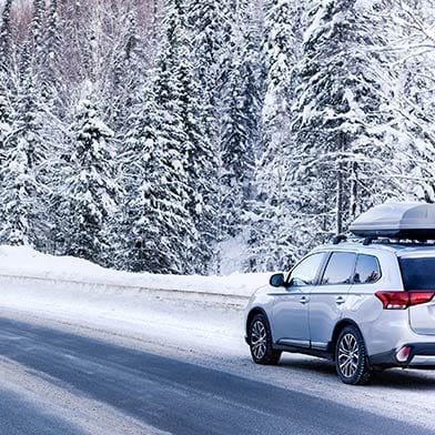 hatchback car driving through snow covered forest in winter