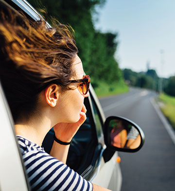 Car passenger leaning out window on scenic highway