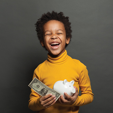 Child holding dollar bill and piggy bank