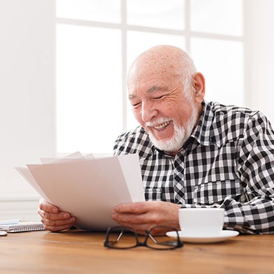 Older man sitting at table, smiling and looking through papers