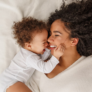 Woman laying down on bed with her baby