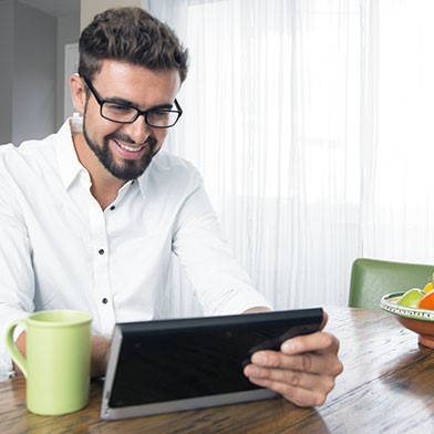 Man using tablet and drinking coffee from a green mug