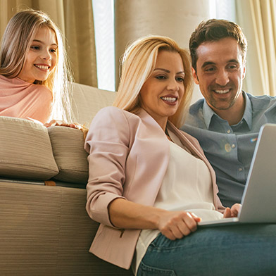 Smiling couple looking at a computer while their daughter looks on.