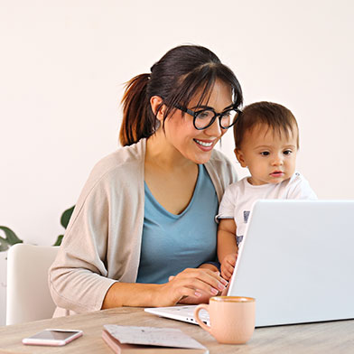 Woman with baby smiling while using laptop