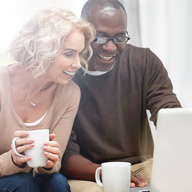 Man and woman smiling looking at a laptop computer