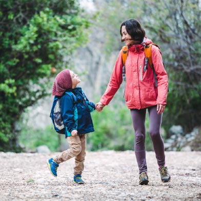 Woman and son in fall gear holding hands and smiling while hiking