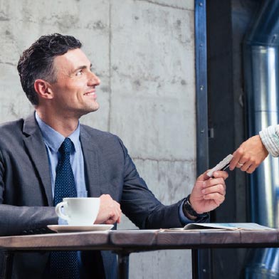 Smiling business man handing debit card to waitress