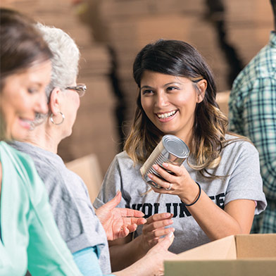 Woman volunteering to sort canned goods at food bank.