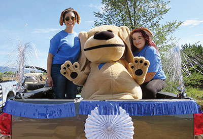 Sunward Employees and Sandy the Lab pose in the back of a decorated truck for the Run, Rally and Rock Parade