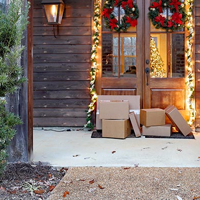 Festively decorated front porch with a pile of cardboard box packages