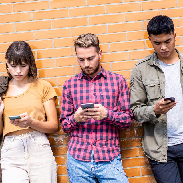 Man holding his phone and looking at it while holding his glasses.