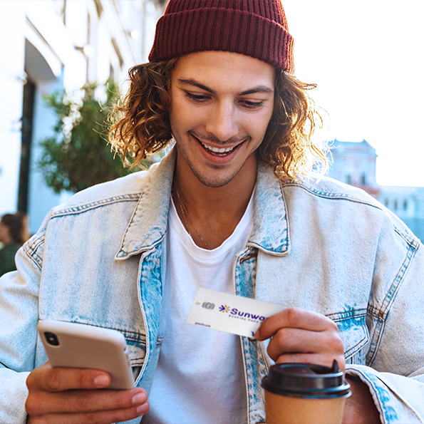 A man with a smart phone holding a Visa Platinum Rebate Credit Card
