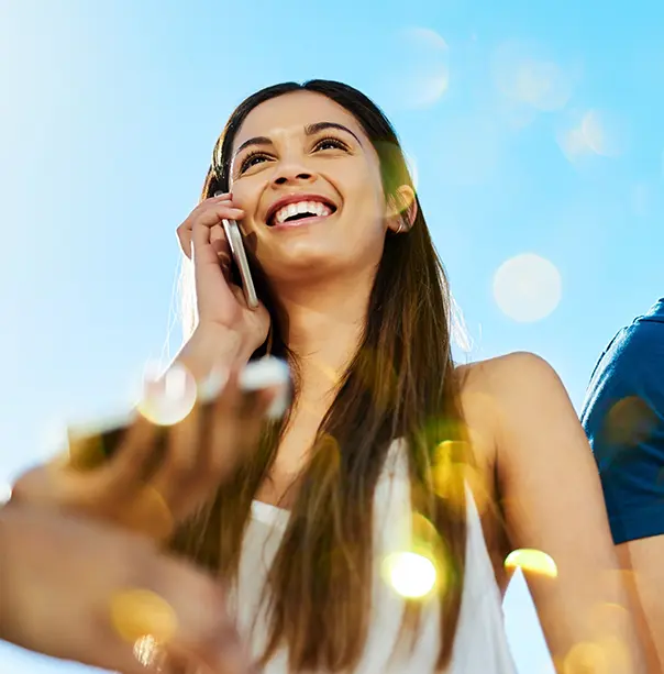 A young woman outside, talking on a smartphone